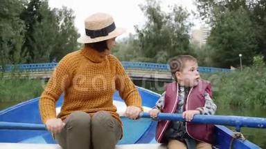 可爱的小孩和奶奶在公园里休息。 可爱的<strong>男孩</strong>在公园的湖边<strong>划船</strong>。 小<strong>男孩</strong>坐在船上拿着桨。 HAP